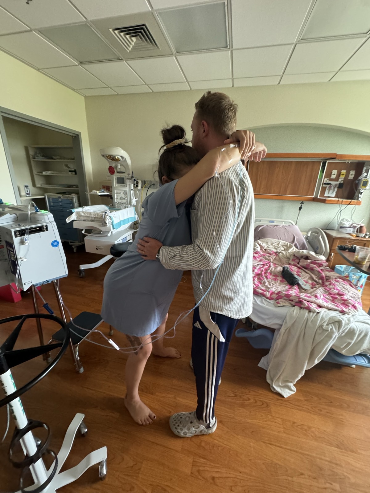 A mother in labor resting in her partner's arms.