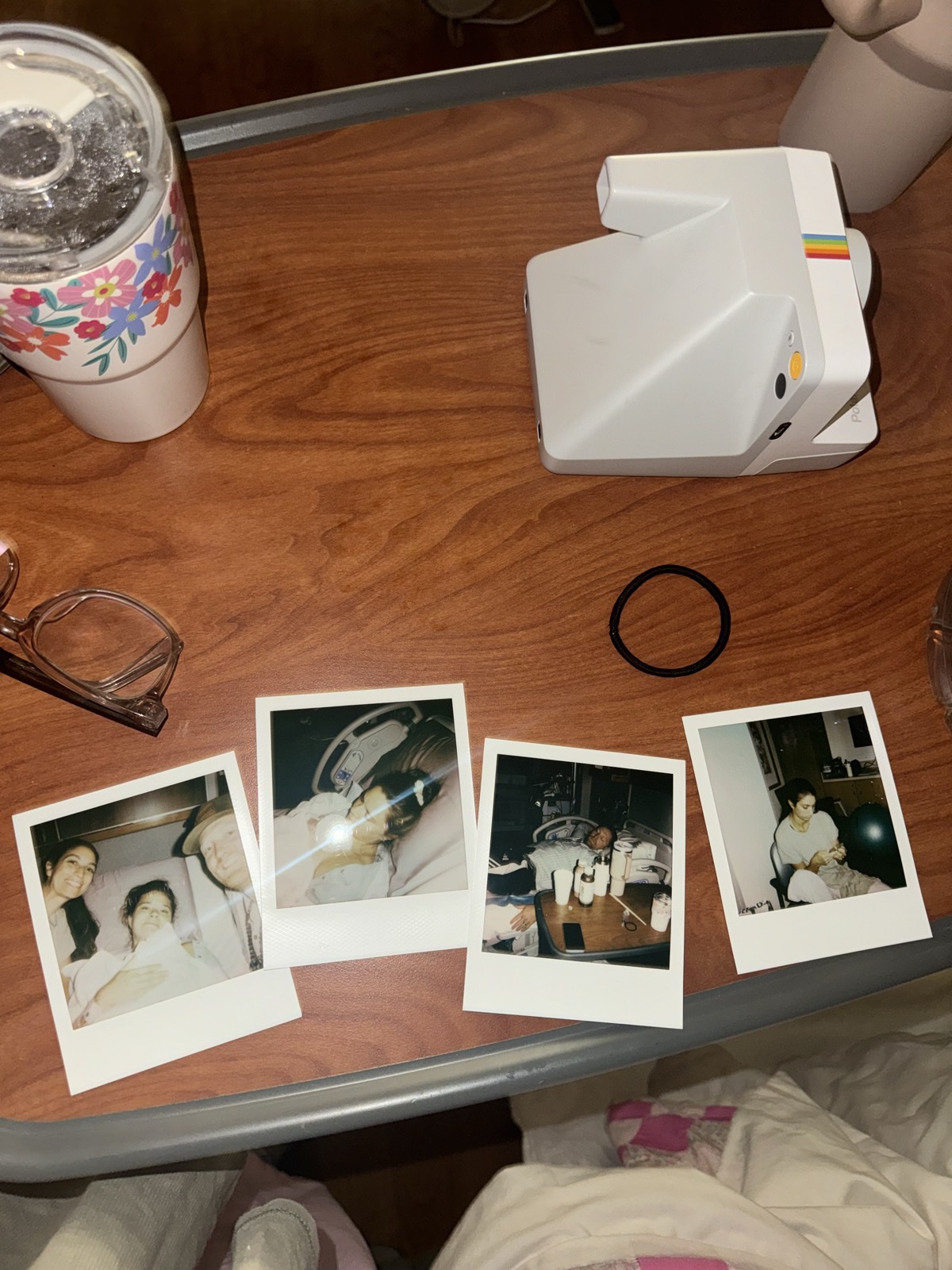 Polaroid photographs from a birth laid out on a hospital bedside table next to an instant camera.